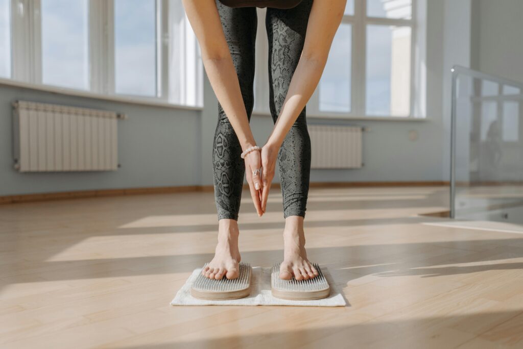 An adult woman performs yoga on a sadhu board indoors, focusing on balance and mindfulness.